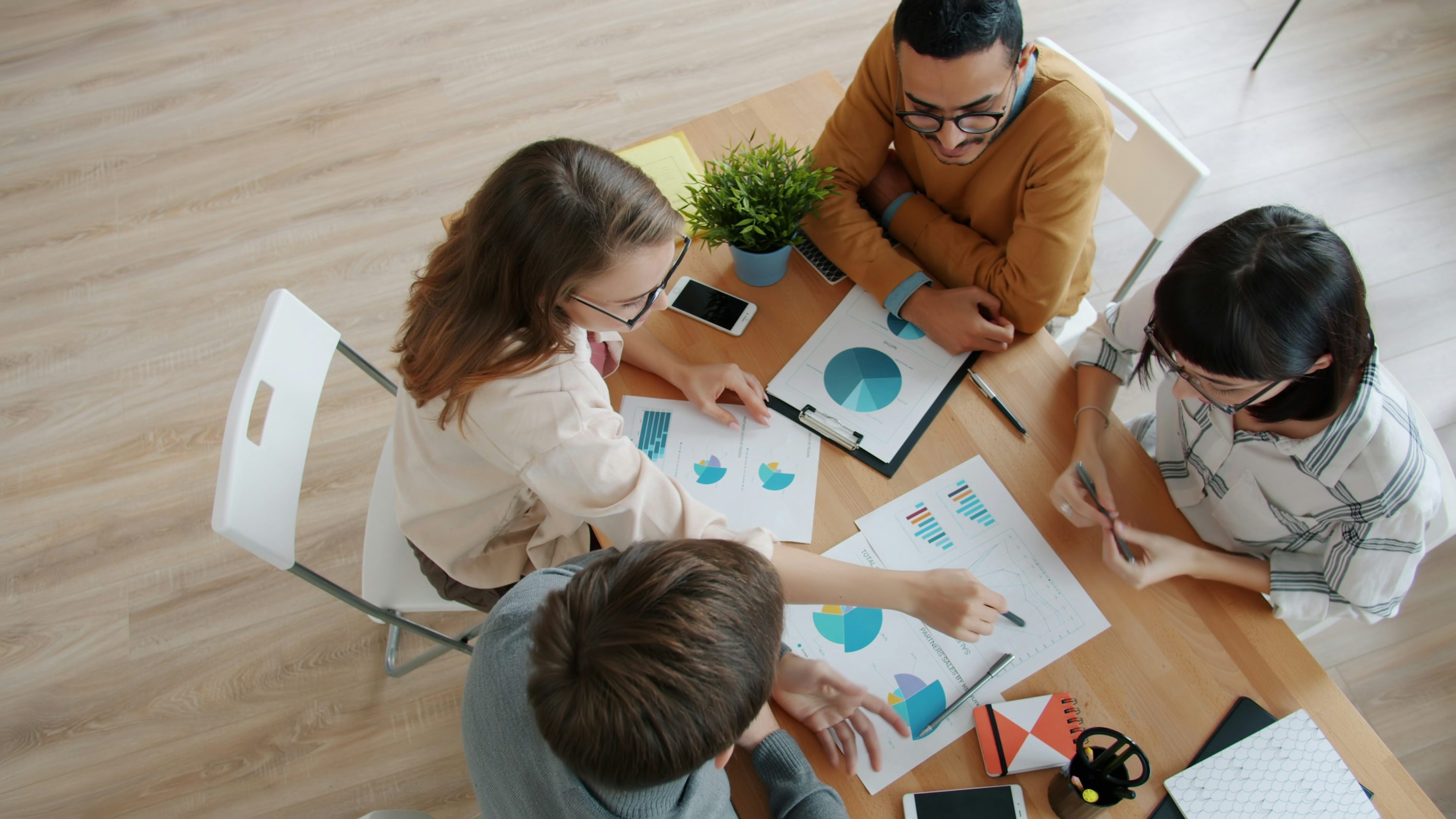 Professionals collaborating around a table with laptops showing data analytics